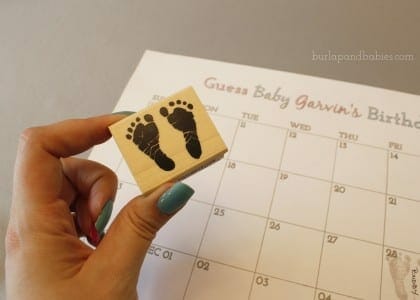 Hand holding an ink stamp with baby feet on it image.