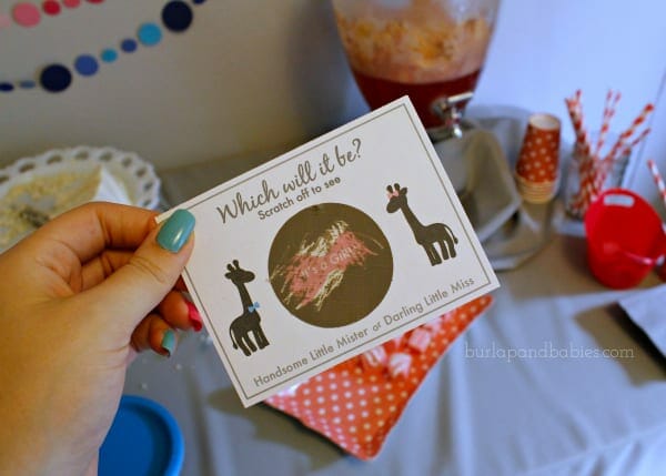 Hand holding a gender reveal scratch off card image.