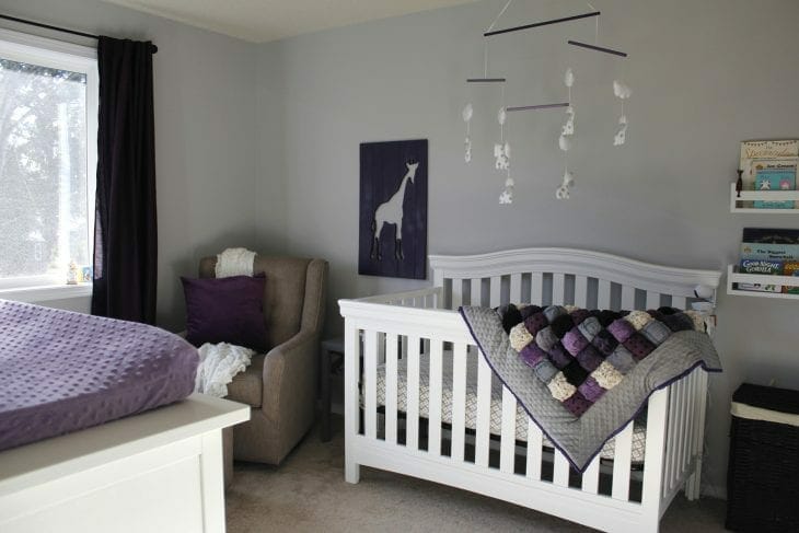 Purple baby nursery with purple puff quilt draped across white crib image.
