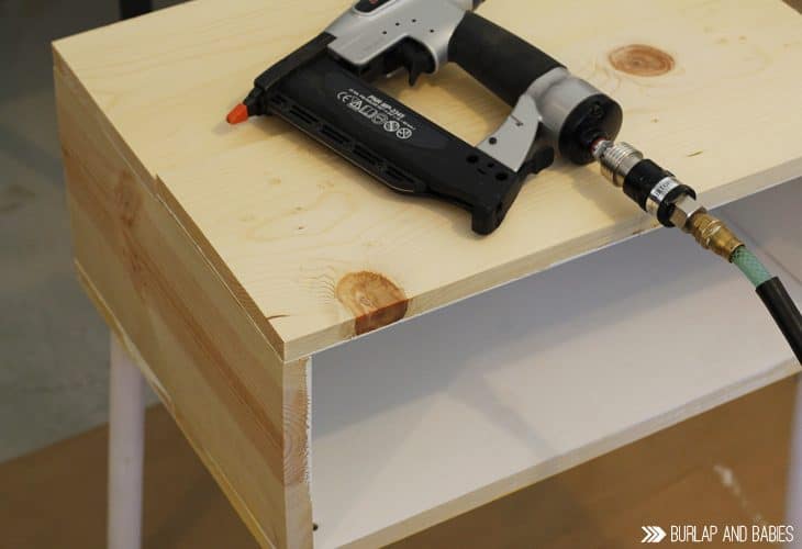 Power tool laying on top of unfinished wooden side table image.