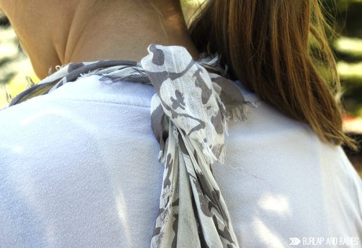 Woman showing how a scarf is tied at the back of her neck image.