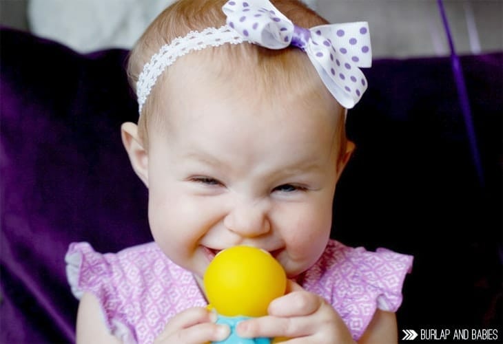 Little baby girl smiling with yellow toy image.