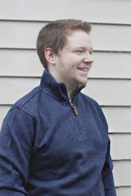 Man smiling in half-zip sweater image.