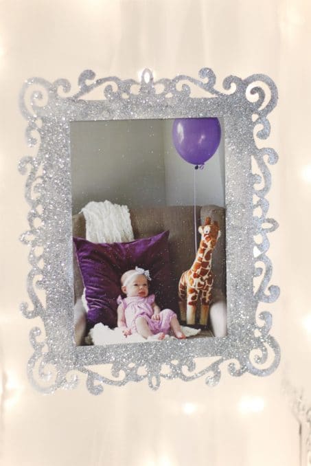 Frame covered in silver glitter featuring a picture of a baby girl and purple balloons image.