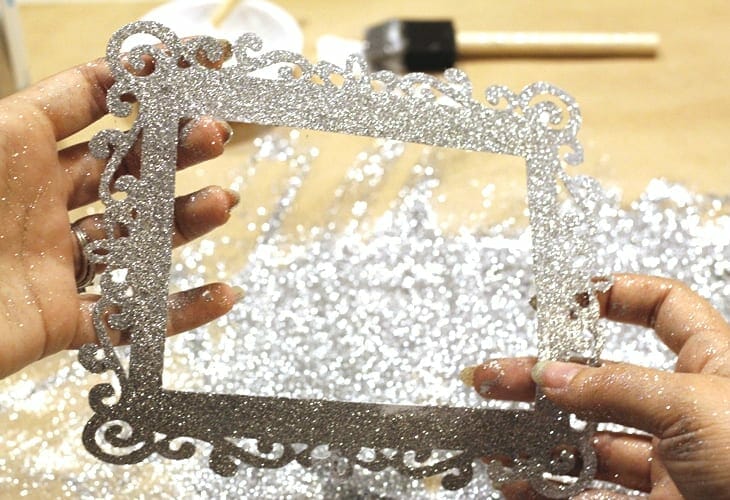 Hands showing frame covered in glued on silver glitter image.