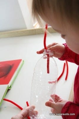 Child putting pipe cleaner in bottle image.