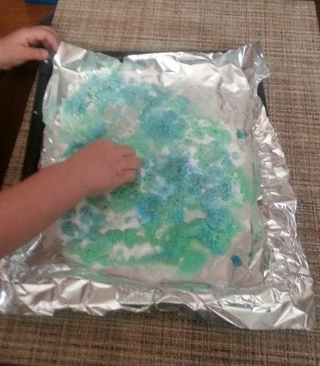Little hands doing a science project with foil image.