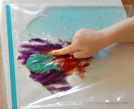 Child's hands playing with a plastic bag filled with tactile ingredients image.