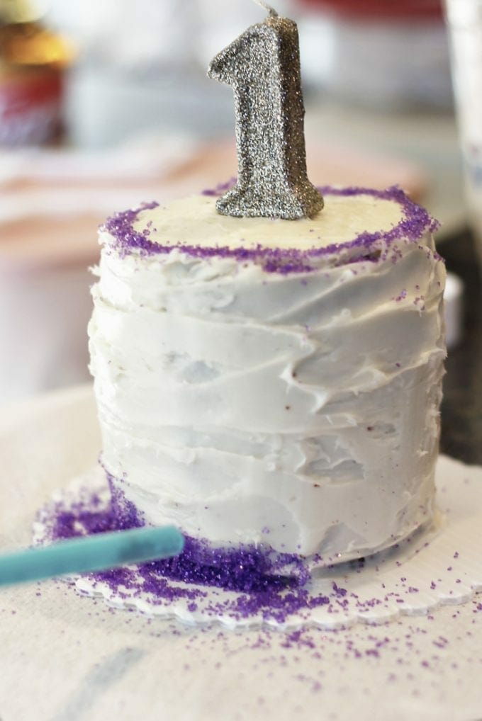 White smash cake with number one candle on top image.