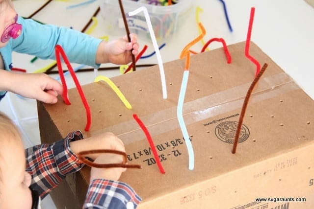 Children putting pipe cleaners in a box with holes in it image.