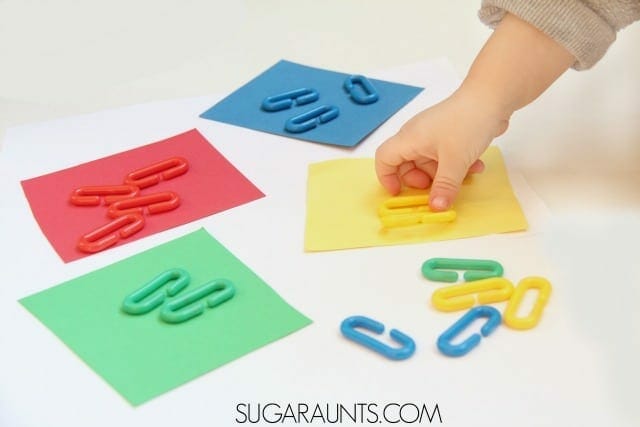 Child's hand matching objects with the right color image.