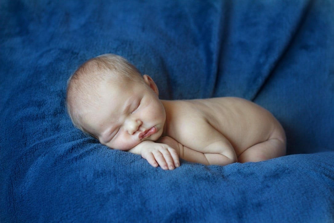 Little baby boy asleep on blue plush image.