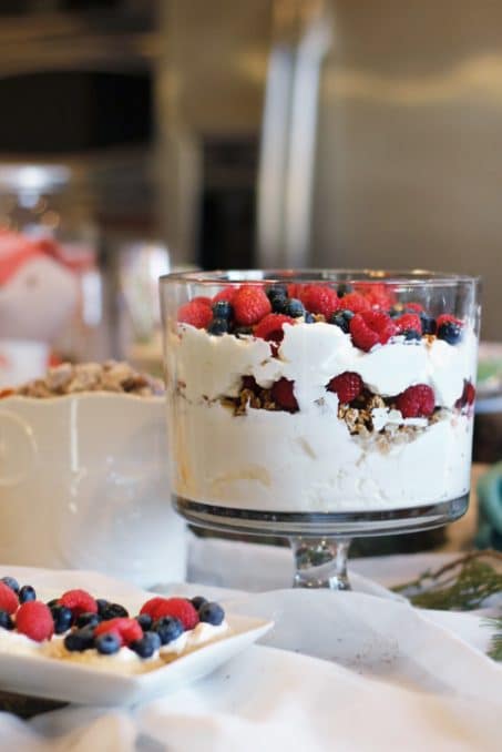 Layered dessert with red and blue berries in clear glass bowl image.