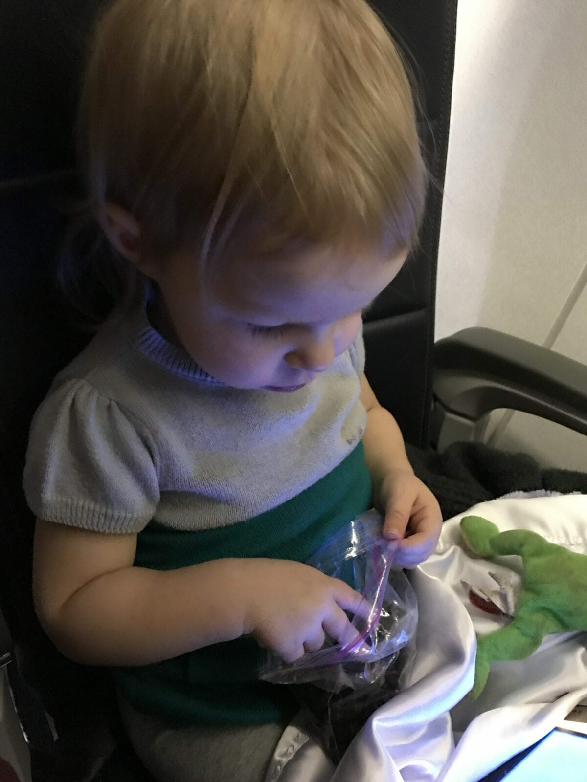Child on plane eating grapes and watching iPad image.