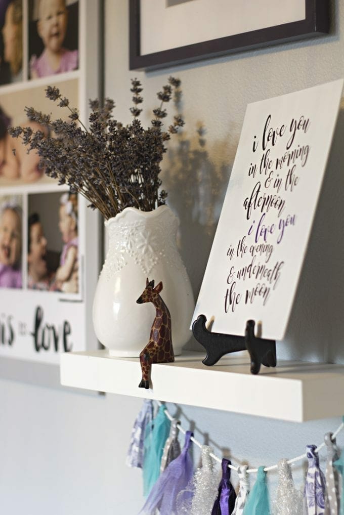 Floating shelf with a quote, a vase, and a giraffe image.