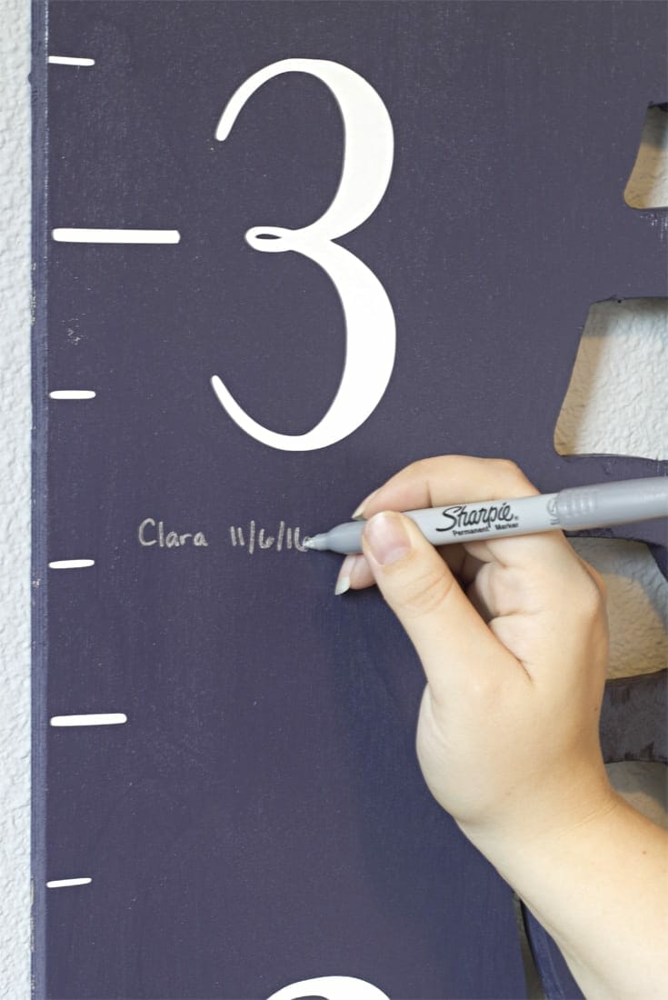 Hand writing a name and height on growth chart image.