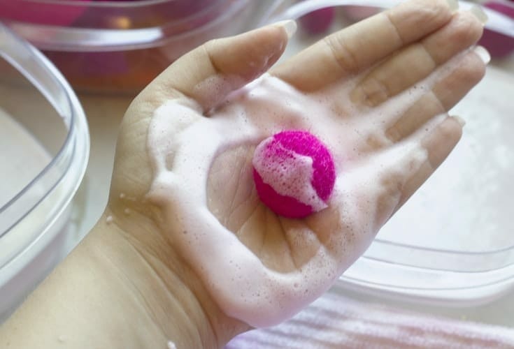 Pink felt ball in hand with white suds image.