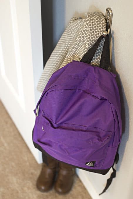 Purple backpack hanging on hook image.