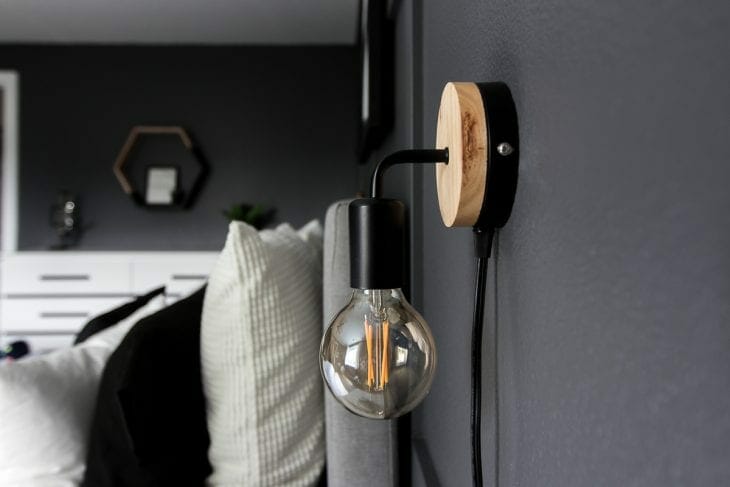 Minimalist wall sconce above nightstand in modern bedroom