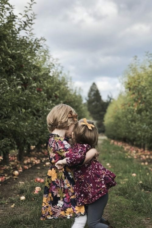 Image of hugging sisters in apple orchard