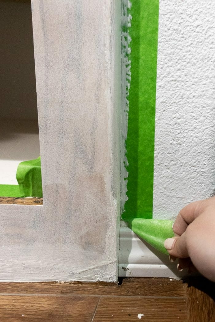 Peeling the green FrogTape from the cabinet corners.