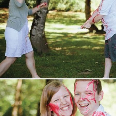 Gender reveal paint fight with smiling couple image.
