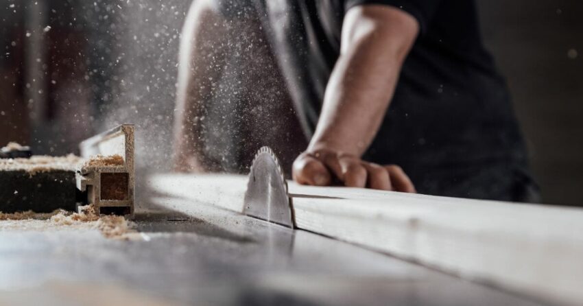 Cutting wood on table saw in workshop