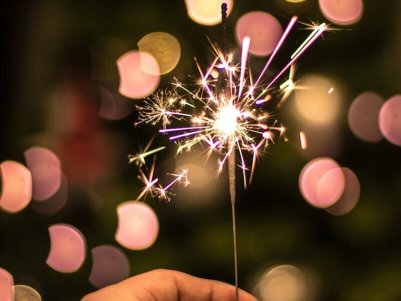 bokeh photography of person holding fireworks