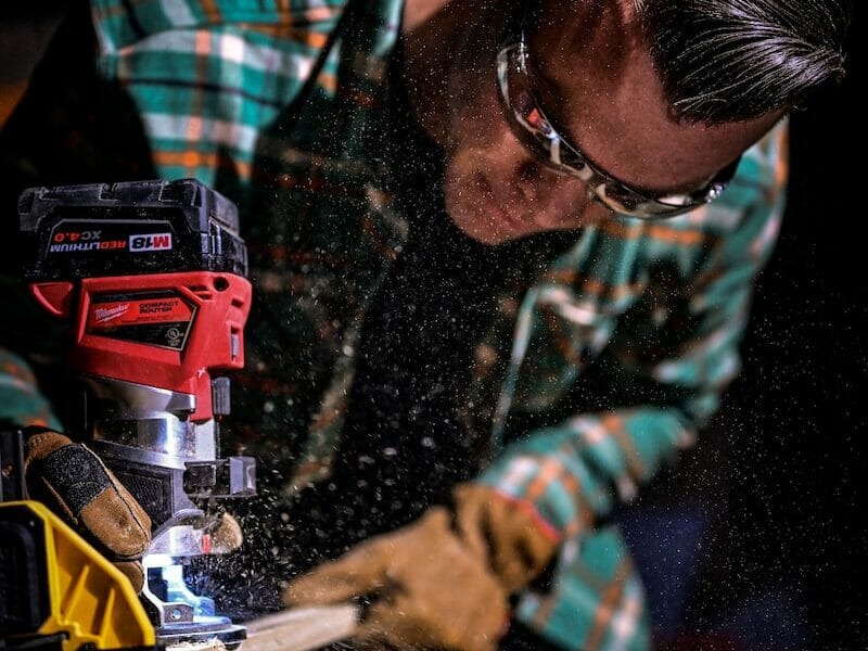 man in green and black plaid long sleeve shirt holding red and black cordless hand drill