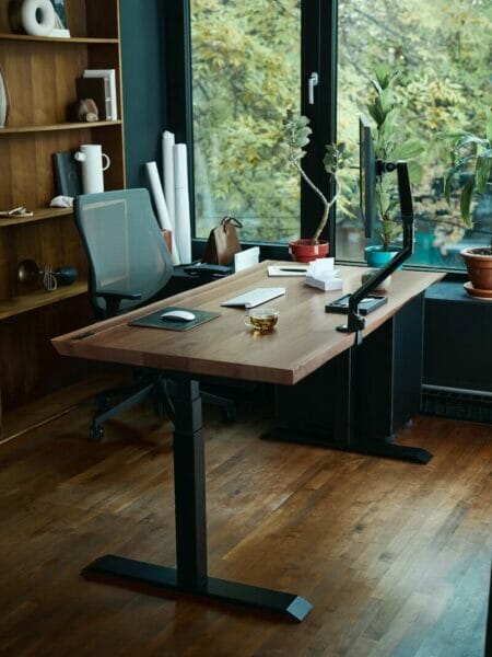 a desk with a laptop on it in front of a window