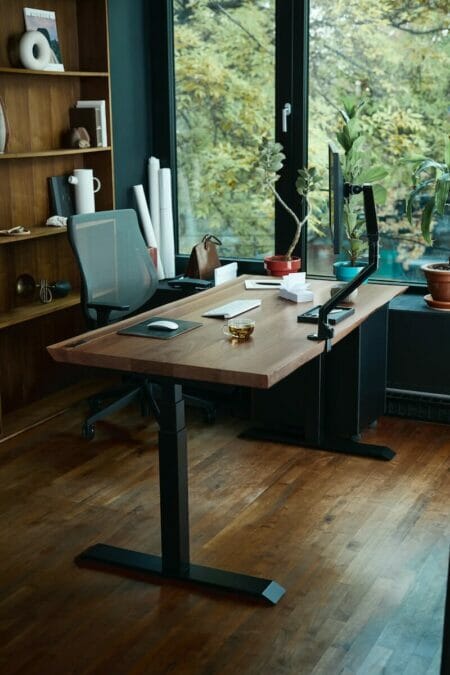 a desk with a laptop on it in front of a window
