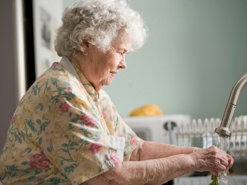 woman in yellow and green floral shirt holding white ceramic mug