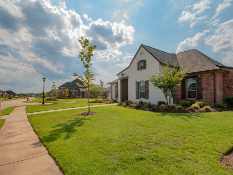 white and brown house near green grass field under white clouds and blue sky during daytime