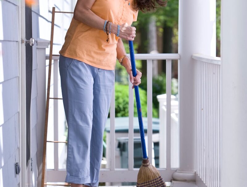 woman in yellow tank top and blue denim skirt holding broom