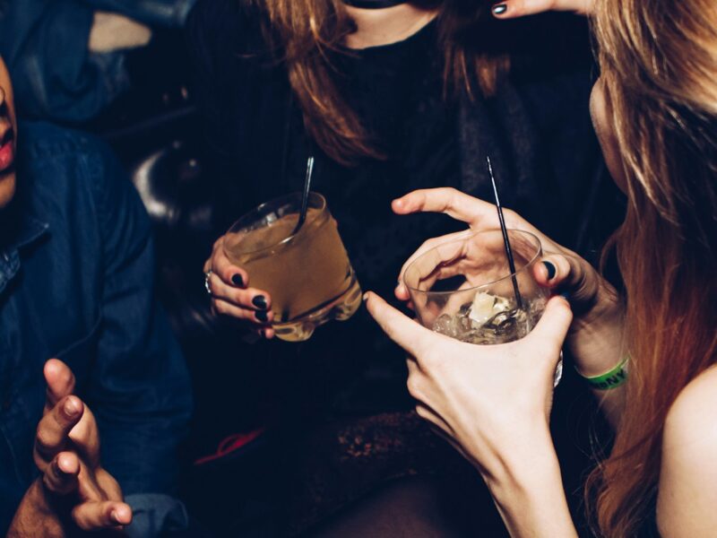 two women talking while holding drinking glasses
