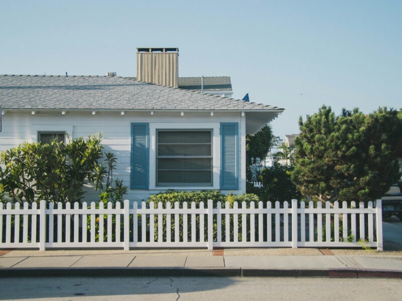 white and blue house beside fence