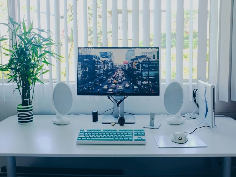 black flat screen computer monitor; keyboard; speakers; mouse on desk