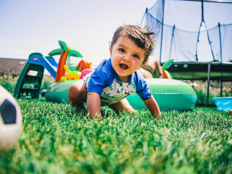 boy in blue and white crew neck t-shirt sitting on green grass field during daytime