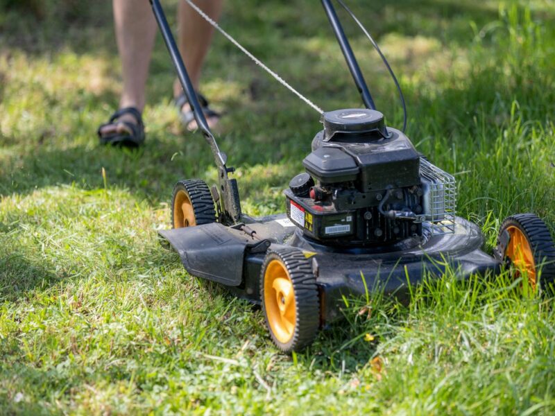 a person mowing the grass with a lawn mower
