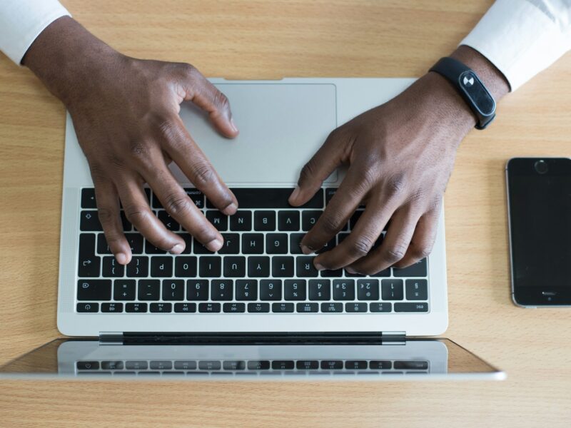 person's hand on MacBook near iPhone flat lay photography