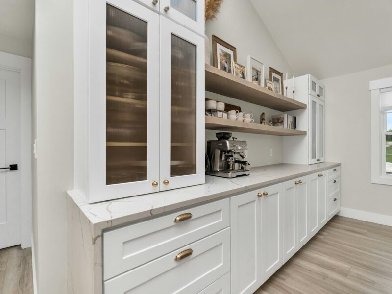 a kitchen with white cabinets and wood floors