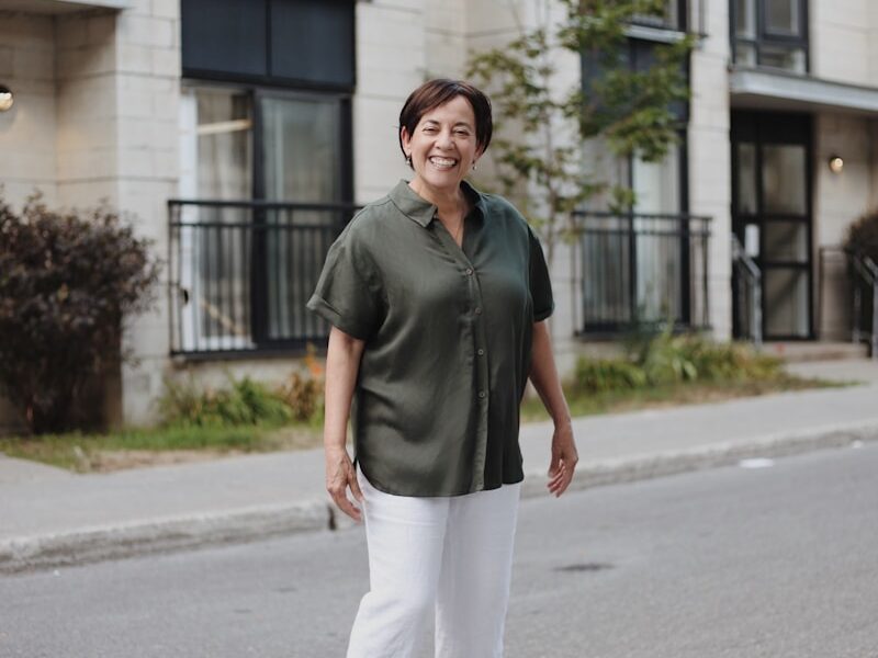 man in green polo shirt and white pants standing on road during daytime