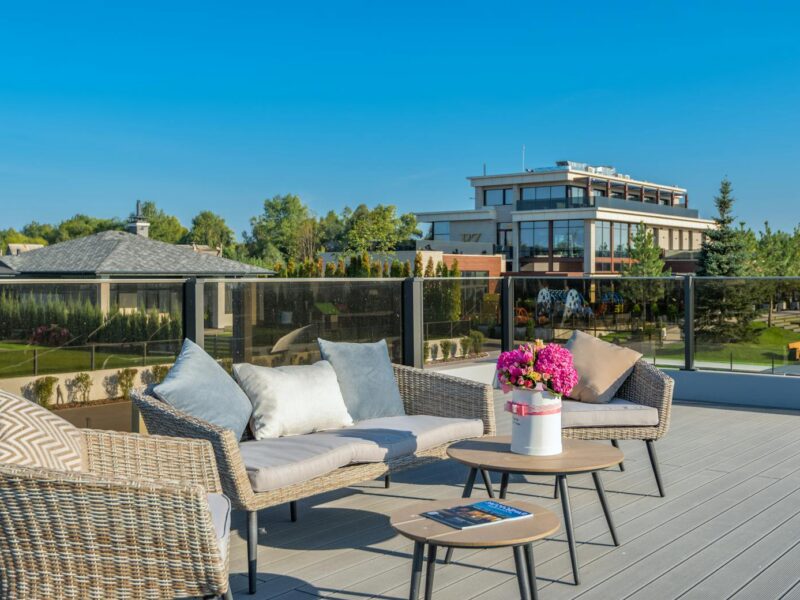 Outdoor terrace with seating and view of modern buildings under clear sky.