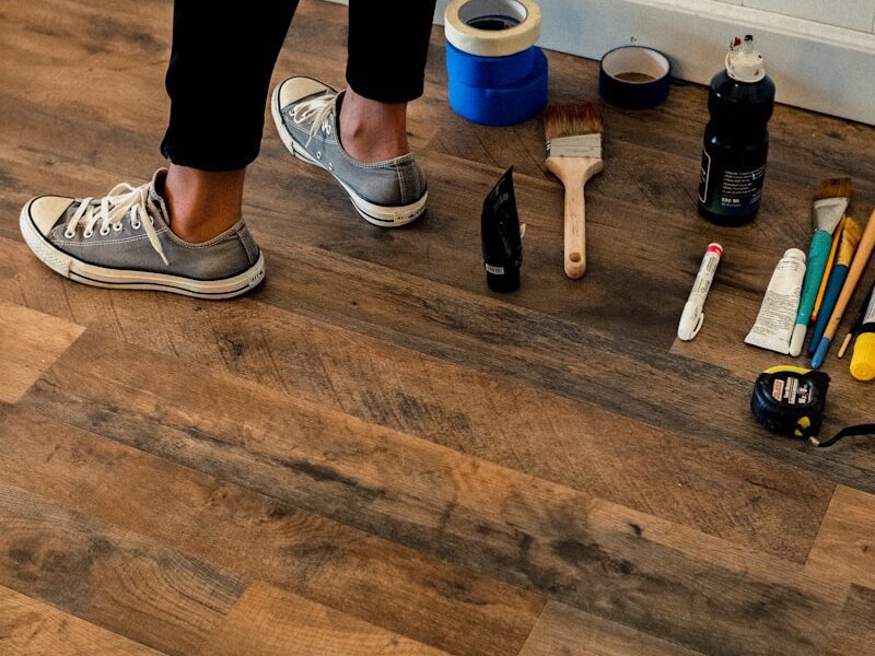 person in black pants and white and black nike sneakers standing on brown wooden floor