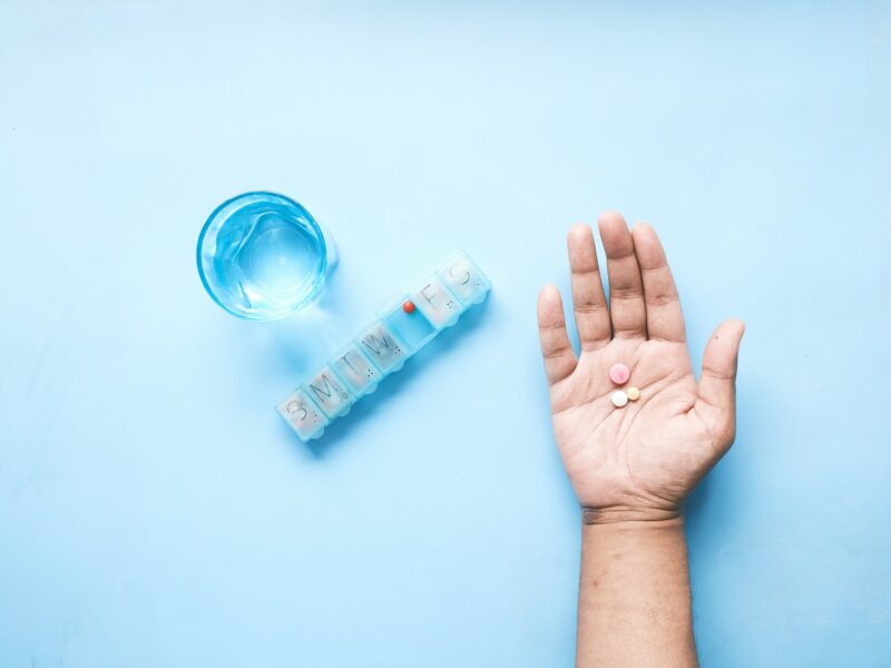 person holding pink and white medicine pill