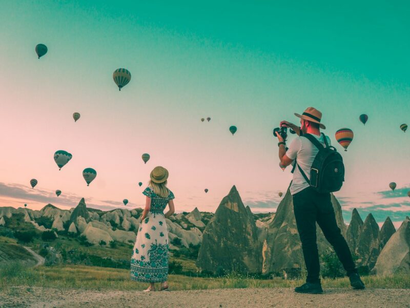 man taking photo of hot air balloons