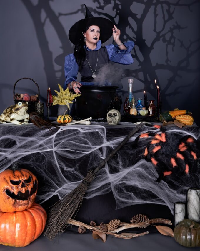 A woman dressed as a witch preparing a table for halloween