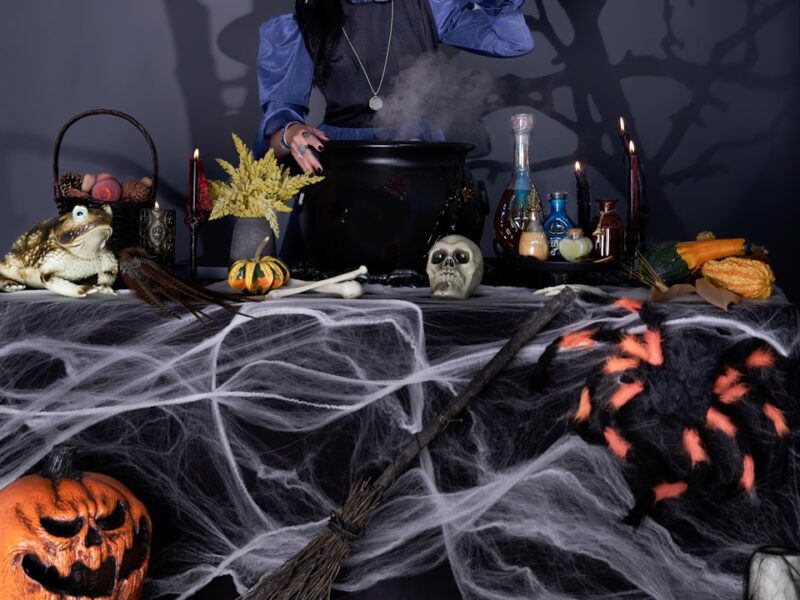 A woman dressed as a witch preparing a table for halloween
