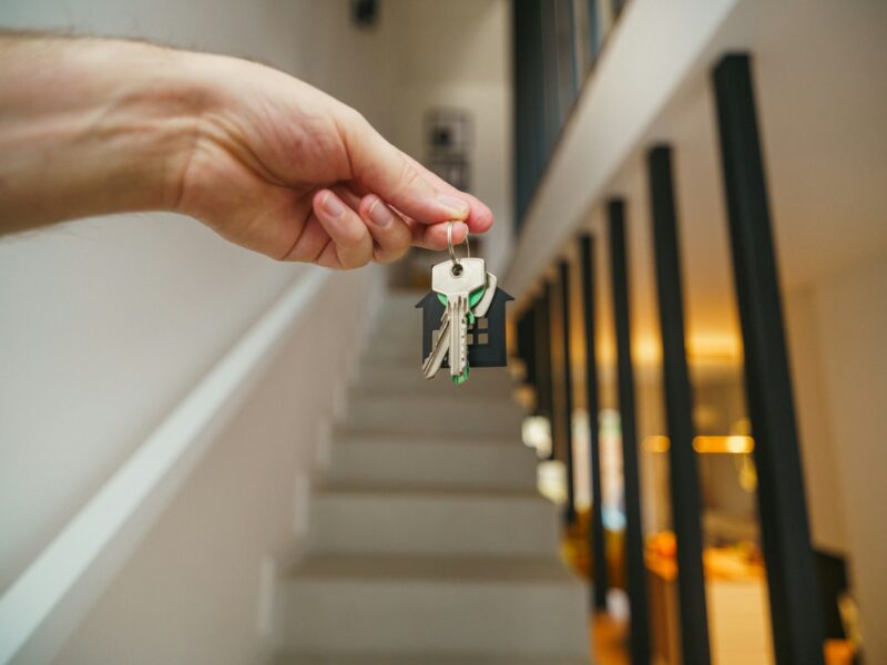 Here's a possible caption: keys being held in front of a staircase.