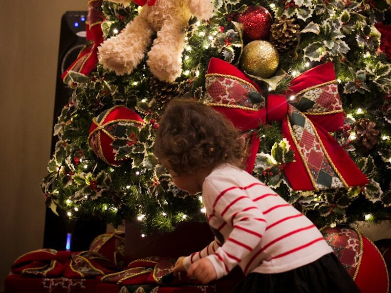girl picking gift in front of pre-lit tree